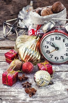 An alarm clock and bag of nuts on the background of Christmas decorations