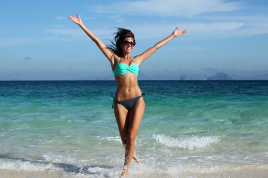 Beautiful happy woman in bikni run on tropical beach