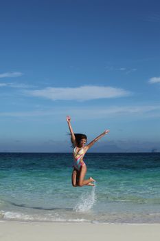 Beautiful happy woman in bikni jump on tropical beach