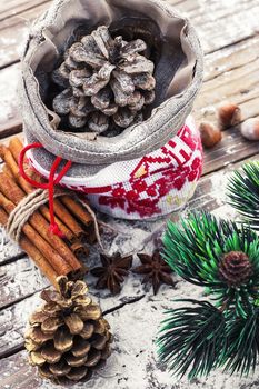 Christmas bag with pine cones on wooden snowy background