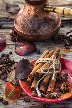 Stylish porcelain Cup of coffee on  background decorated with spices and strewn with autumn leaves