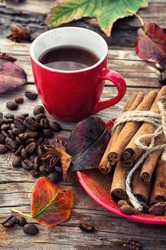 Stylish porcelain Cup of coffee on  background decorated with spices and strewn with autumn leaves