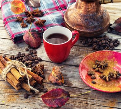 Cup of black coffee on background with warm blanket strewn with autumn leaves