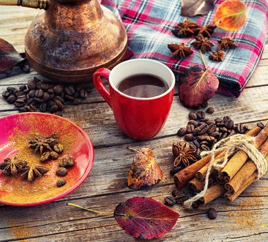 Cup of black coffee on background with warm blanket strewn with autumn leaves