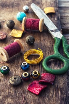 Beads,thread,wire and tools for needlework on the old wooden background