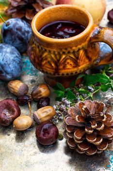 Stylish cup of autumn tea infused with herbs on the background of the fruit