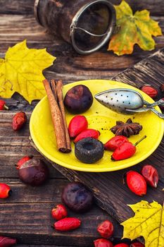 custard teaspoon on the saucer with yellow spilling rose hips and leaves on the table