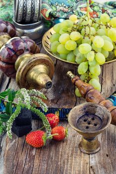 Hookah with fruit flavour on wooden table in vintage style