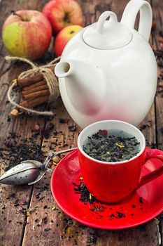 White teapot and Cup with red Apple tea with cinnamon in a rustic style.