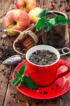 Red cup and saucer of herbal tea with apples and cinnamon sticks