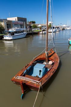 a newly restored vintage wooden sailboat moured at a small marina in Melbourne.