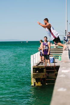 MELBOURNE/AUSTRALIA - FEBRUARY 6: Youths jump off a jetty into the water, while others fish in Mordialloc, a coastal suburb of Melbourne, Australia in February.