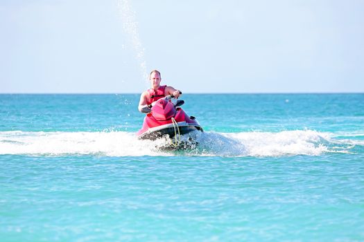 Young guy cruising on a jet ski on the caribbean sea