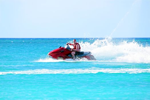 Young guy cruising on a jetski on the caribbean sea