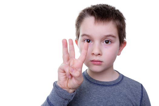 Close up of serious little boy gesturing with three fingers as if to count or display a symbol