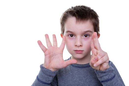 Cute serious little boy gesturing with seven fingers on two hands as if to count or display a symbol