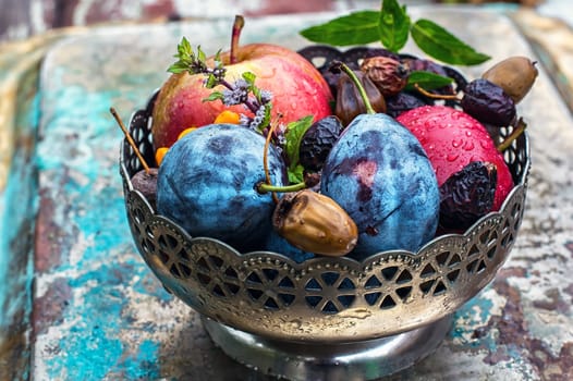 Ripe autumn apple and plum in an iron vase.