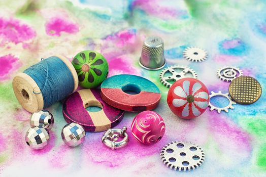 spool of thread with beads and accessories for needlework on bright background