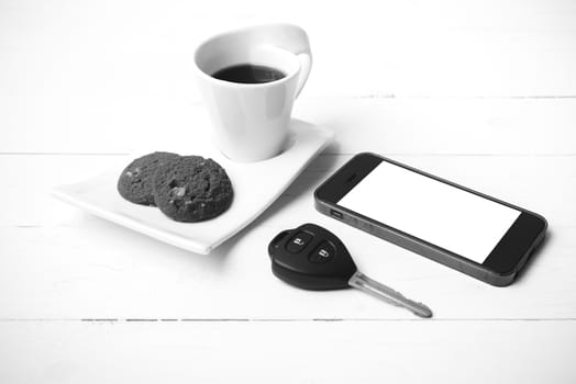coffee cup with cookie,phone and car key on white wood table black and white color