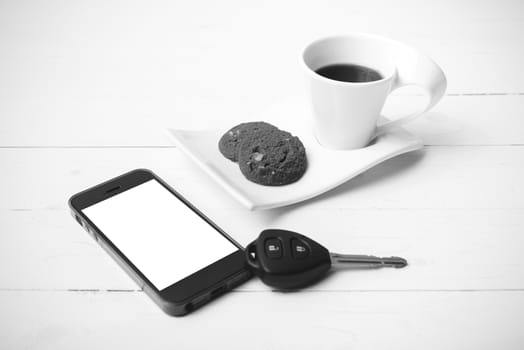 coffee cup with cookie,phone and car key on white wood table black and white color