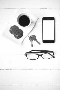 coffee cup with cookie,phone,eyeglasses and key on white wood background black and white color