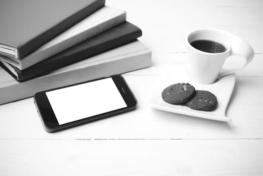 coffe cup with cookie,phone and stack of book on white wood table black and white color