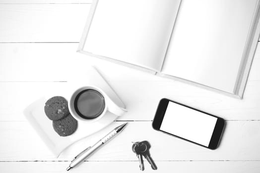 coffee cup with cookie,phone,notebook and key on white wood table black and white color