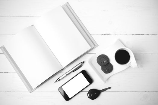 coffee cup with cookie,phone,open notebook and car key on white wood table black and white color