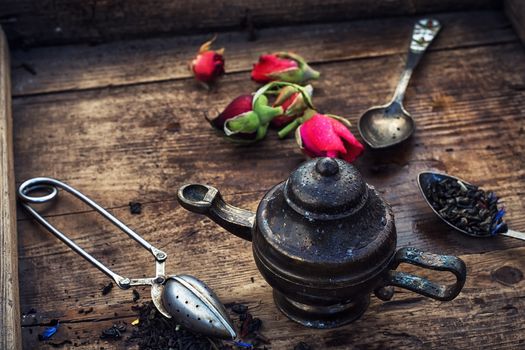 Dried tea leaves in spoons on stylish background of the teapot.