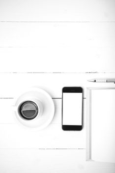 coffee cup with phone and notebook on white wood table black and white color