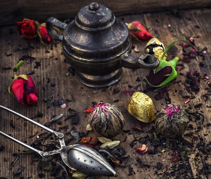 Dried tea leaves in spoons on stylish background of the teapot.