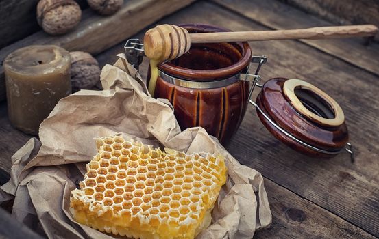 Honeycomb wrapped in grey paper on the background of the jars