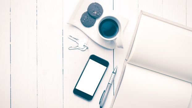 coffee cup with cookie,phone,notebook and key on white wood table vintage style