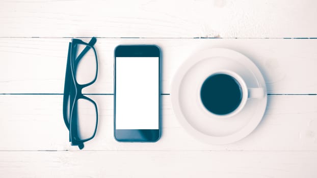 coffee cup with phone and eyeglasses on white wood table vintage style