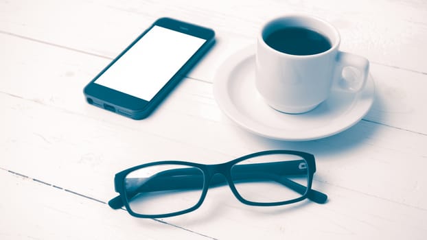 coffee cup with phone and eyeglasses on white wood table vintage style