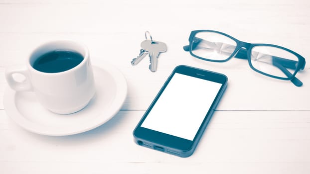 coffee cup with phone, eyeglasses and key on white wood table vintage style