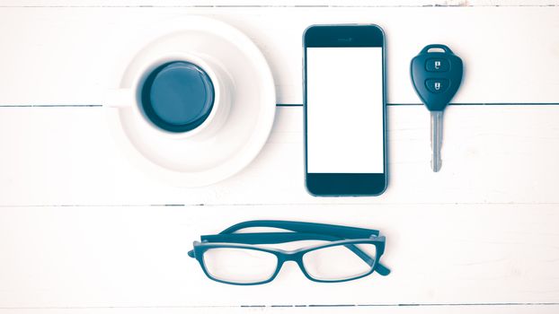 coffee cup with phone, eyeglasses and car key on white wood table vintage style
