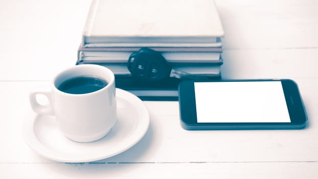 coffee cup with phone,car key and stack of book on white wood table vintage style