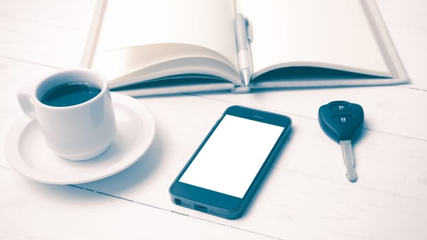 coffee cup with phone,car key and open notebook on white wood table vintage style
