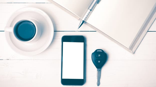 coffee cup with phone,car key and open notebook on white wood table vintage style