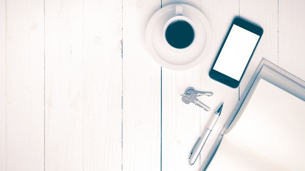coffee cup with phone, key and open notebook on white wood table vintage style