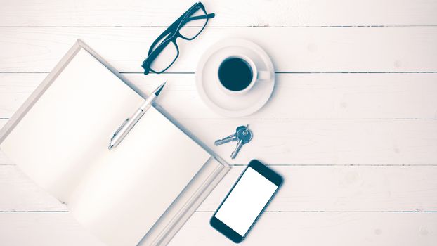 coffee cup with phone, key,eyeglasses and open notebook on white wood table vintage style