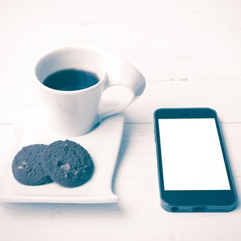 coffee cup with cookie and phone on white wood background vintage style