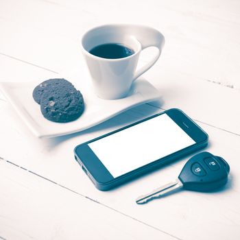 coffee cup with cookie,phone and car key on white wood table vintage style