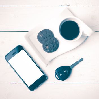 coffee cup with cookie,phone and car key on white wood table vintage style