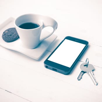 coffee cup with cookie,phone and key on white wood table vintage style