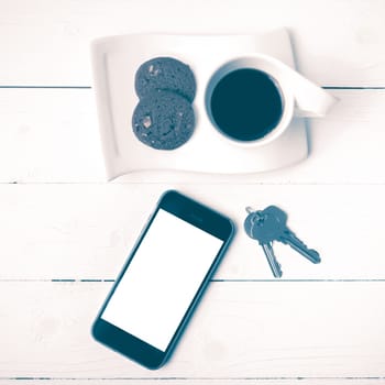 coffee cup with cookie,phone and key on white wood table vintage style