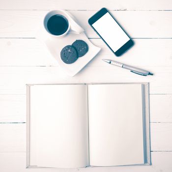 coffee cup with cookie,phone with notebook and pen on white wood table vintage style