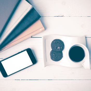 coffe cup with cookie,phone and stack of book on white wood table vintage style