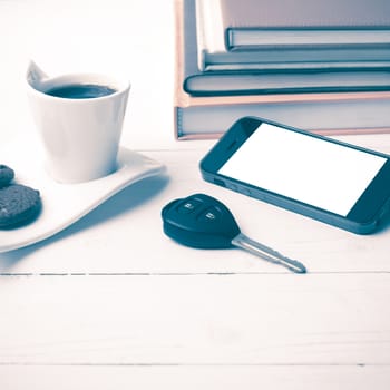coffe cup with cookie,phone,car key and stack of book on white wood table vintage style